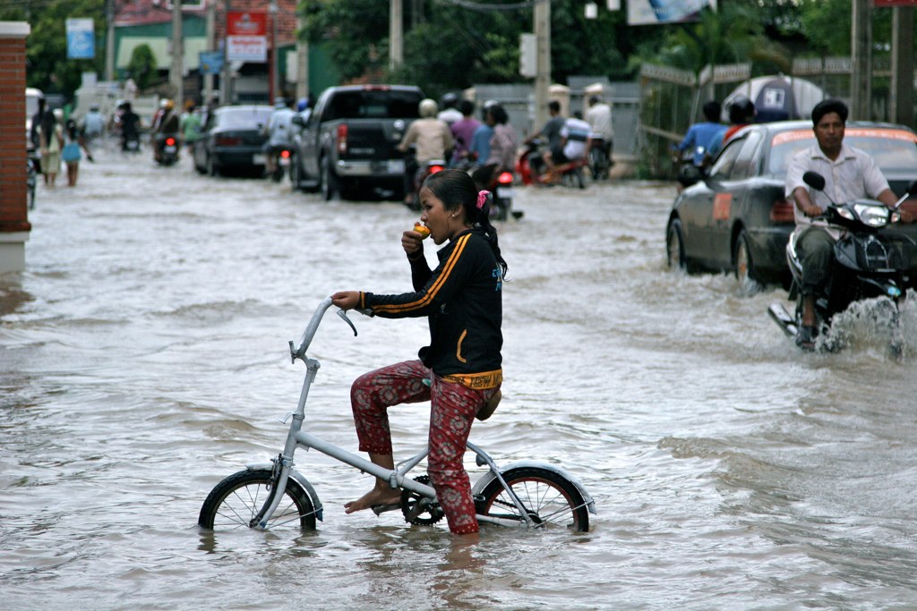 the man is riding his bike through flooded streets