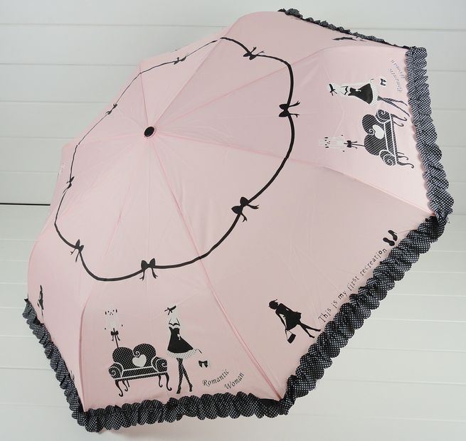the girl holds a pink umbrella with a black pattern on it