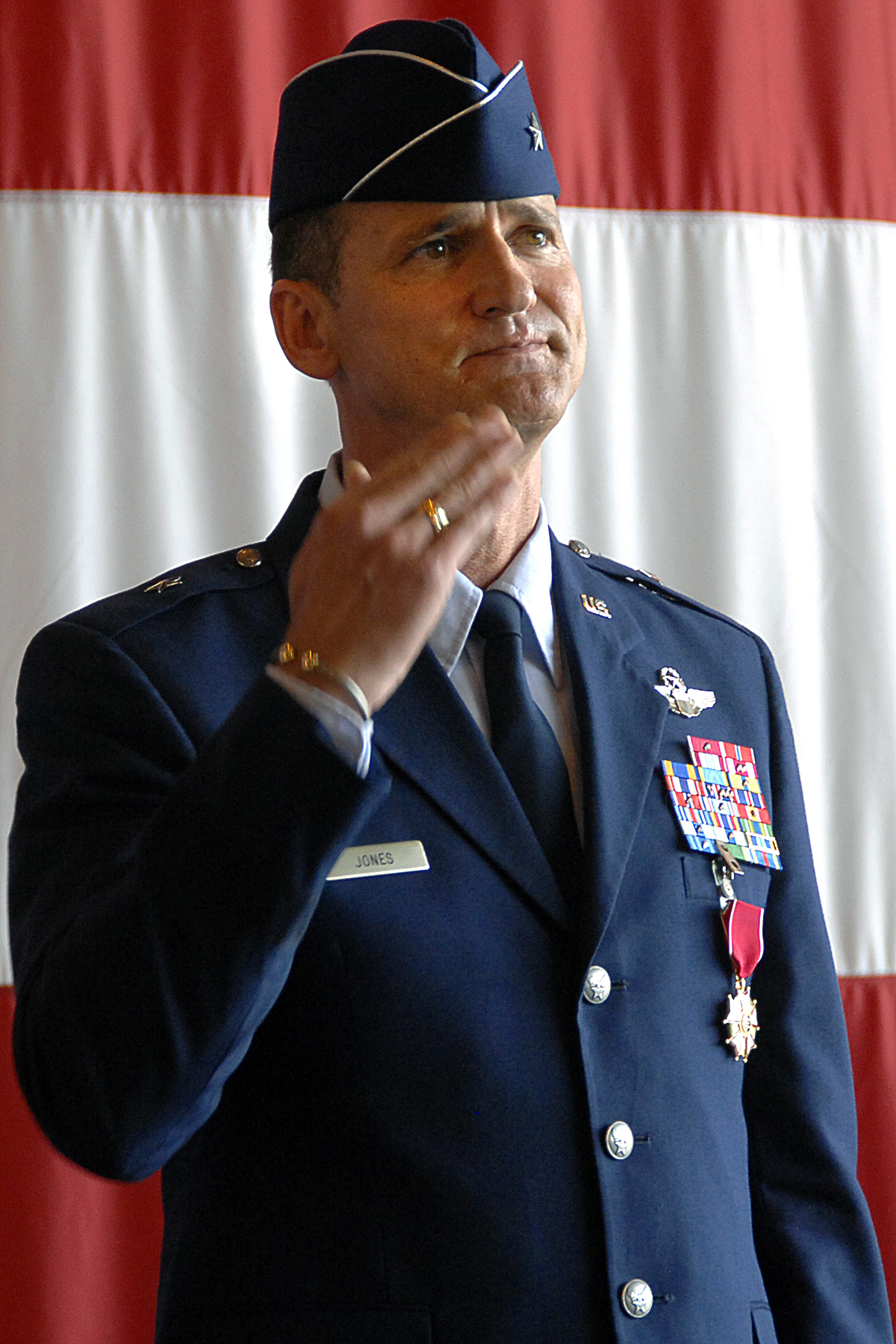 a uniformed person in uniform standing up with a flag behind him