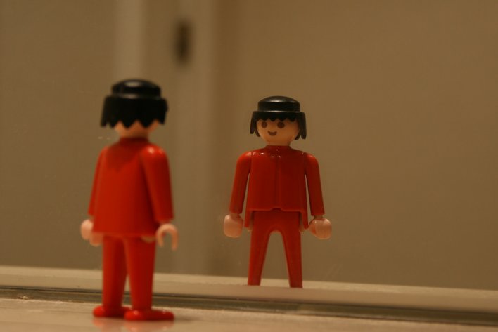 two toy figurines with helmets on looking in the mirror