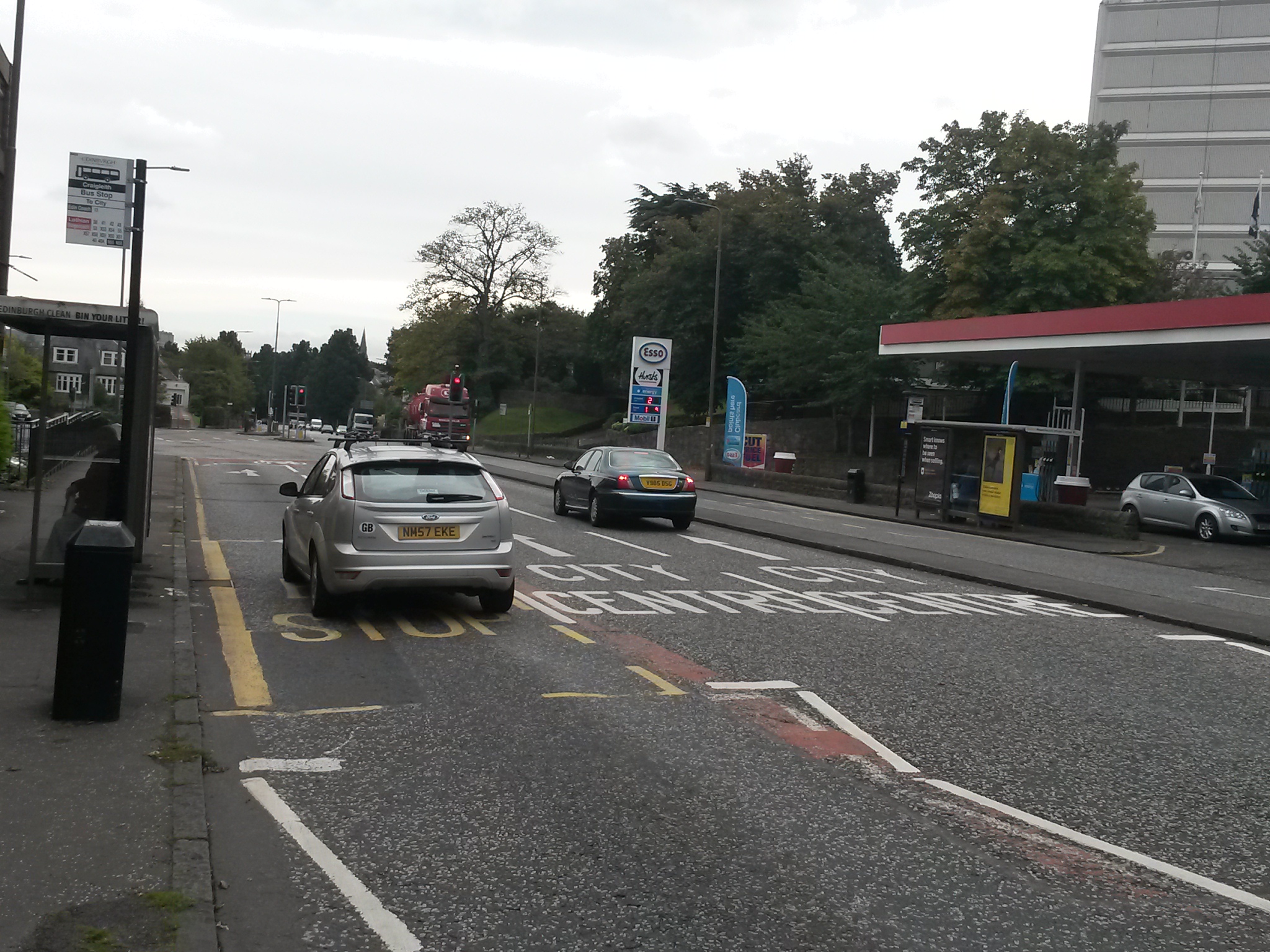 several cars parked on the side of a street near a shopping center