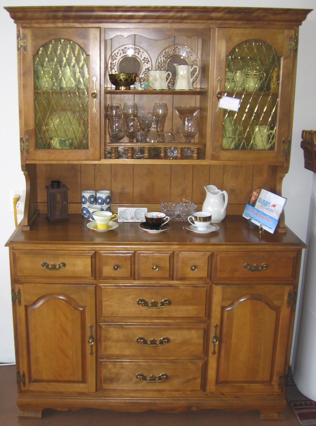 a wooden hutch has plates and cups on it