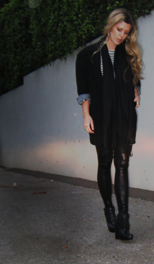 a woman in black standing outside on her phone