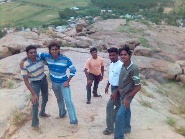 four young men pose together on top of a mountain