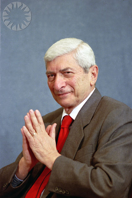 a man in a suit sitting down holding his hands together