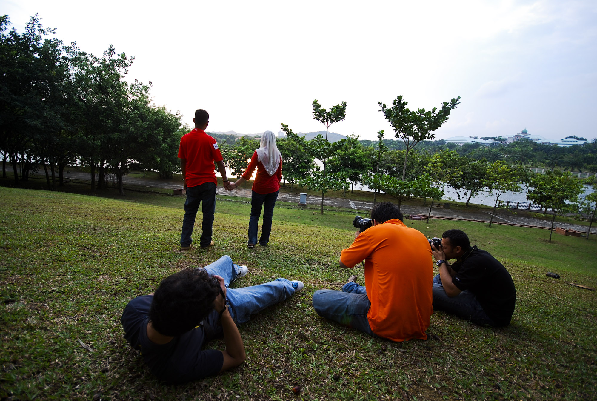 a group of people sit on the grass in front of a lake