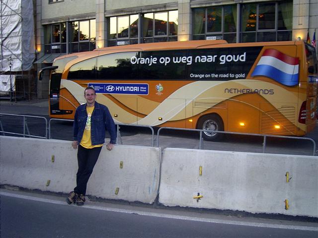 a man standing next to a long bus