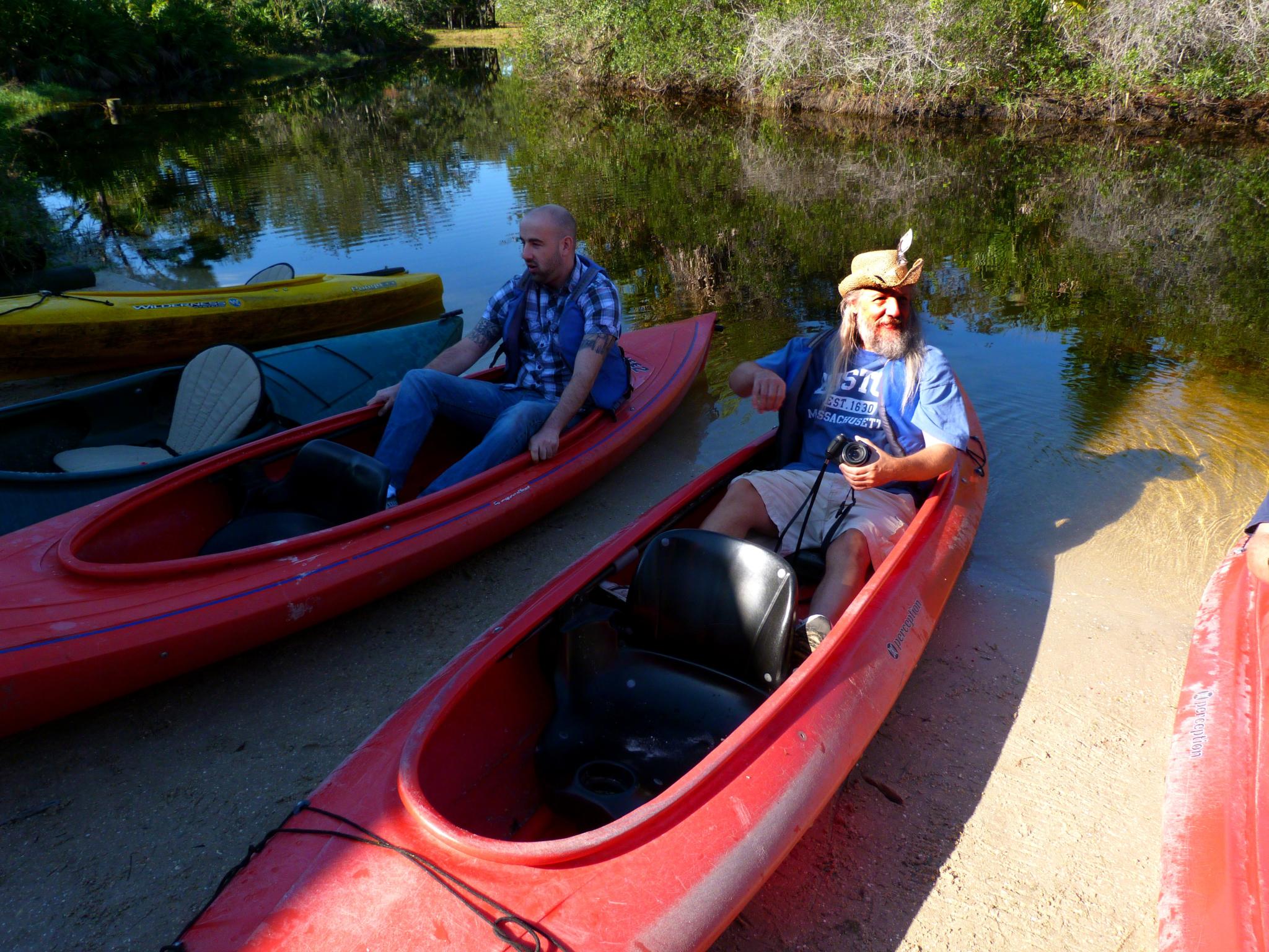 two people sit inside of small red canoes