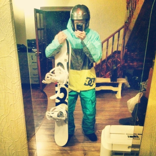 a man holding a snowboard and taking a selfie