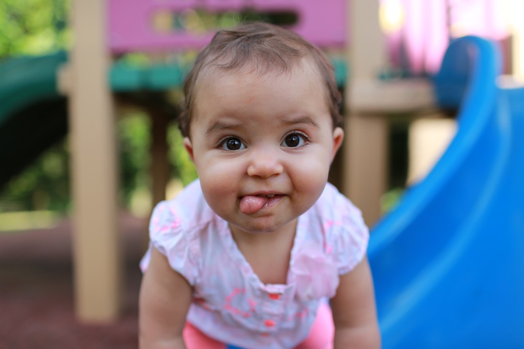 little girl sitting on a plastic bench in a play ground