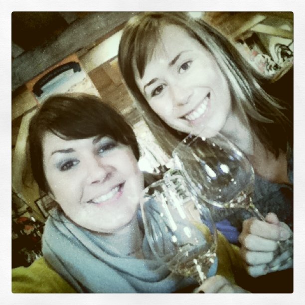 two women pose for a picture with wine glasses