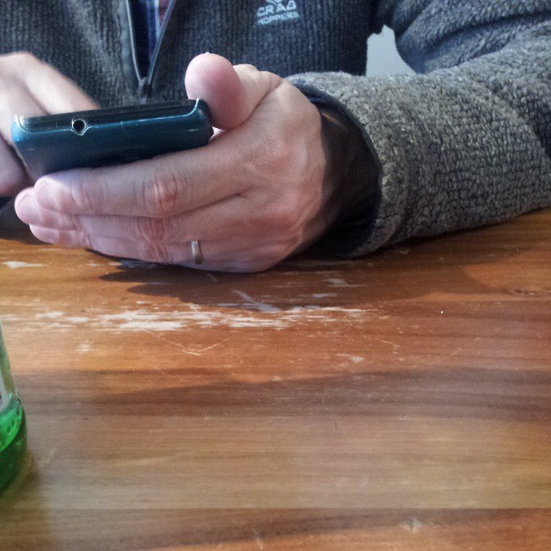 the man is using his cell phone by his soda bottle