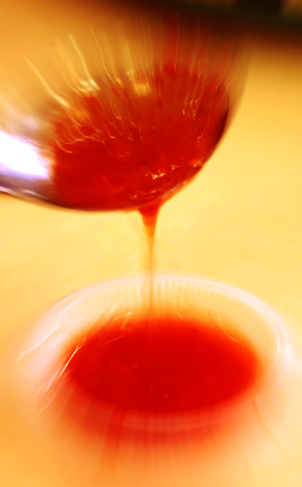 a spoon pouring soing red in some liquid