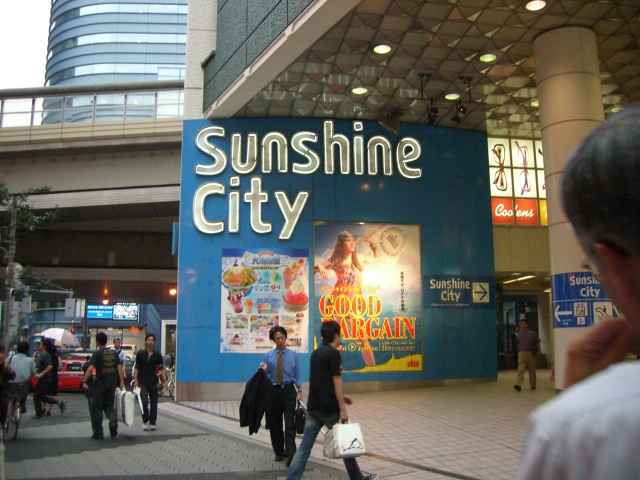 a group of people walking near an advertit for the sun shine city