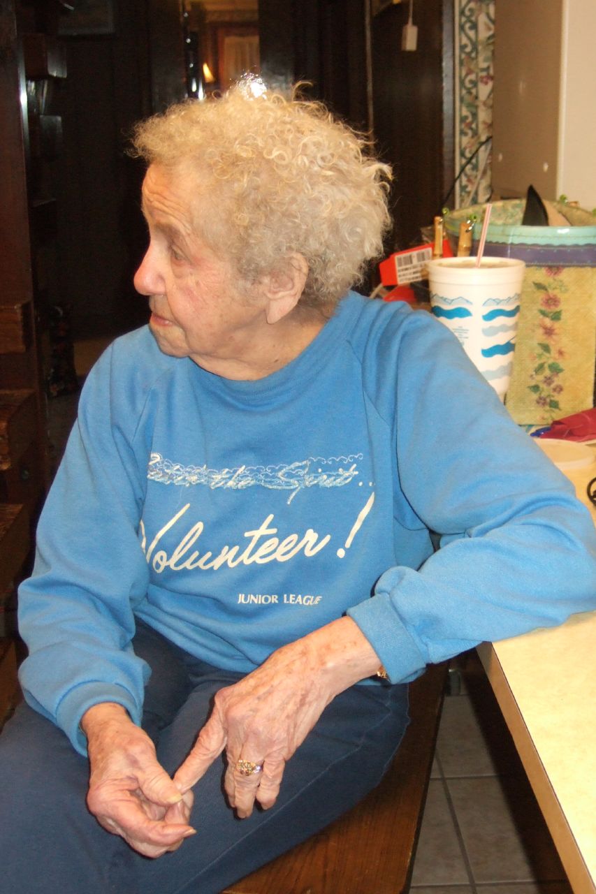 an older woman sitting down wearing blue shirts