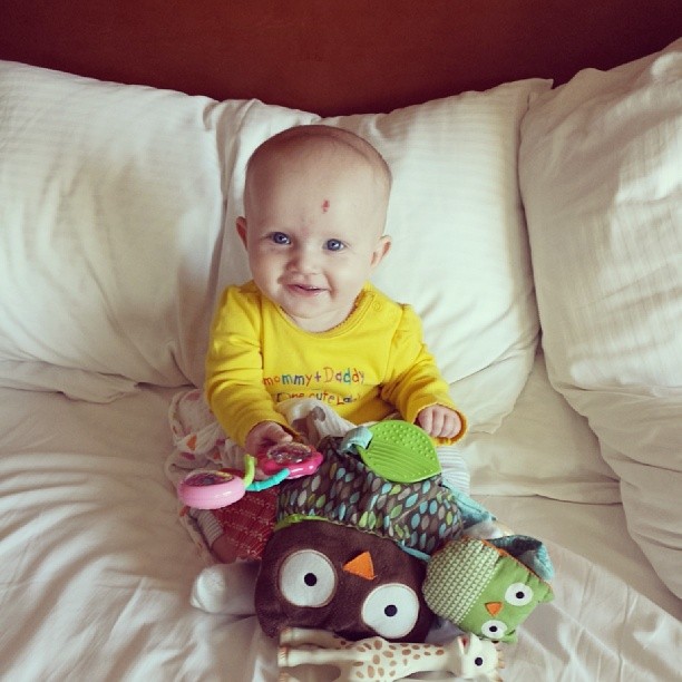 the baby is sitting on top of pillows with toys