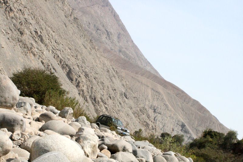 a car parked near a rocky cliff and tree