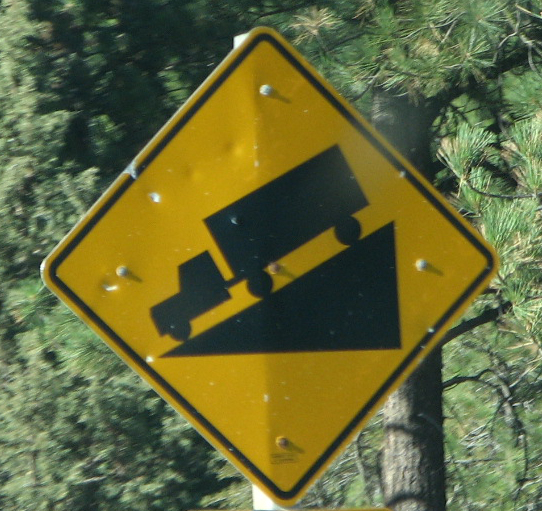 a yellow truck crossing sign on a forest road