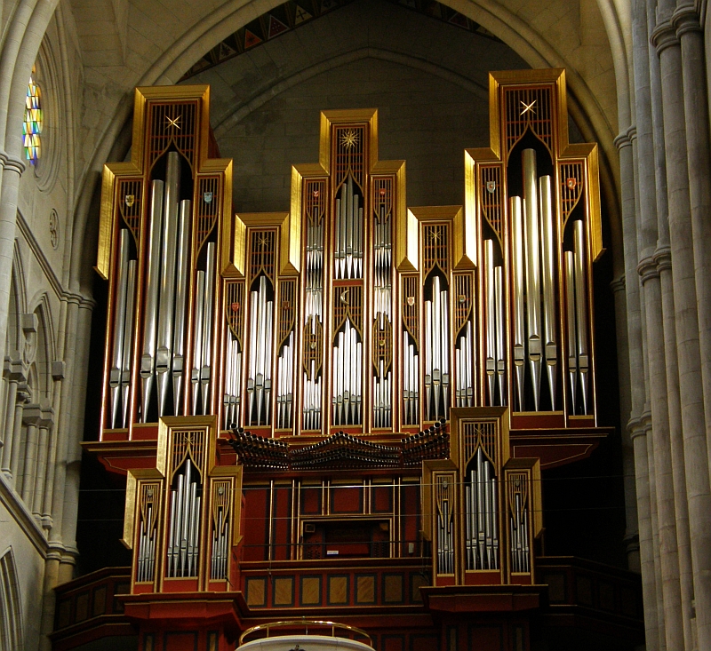 an organ is sitting in a church by a statue