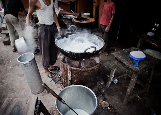 a group of people around a large pot with boiling water inside of it