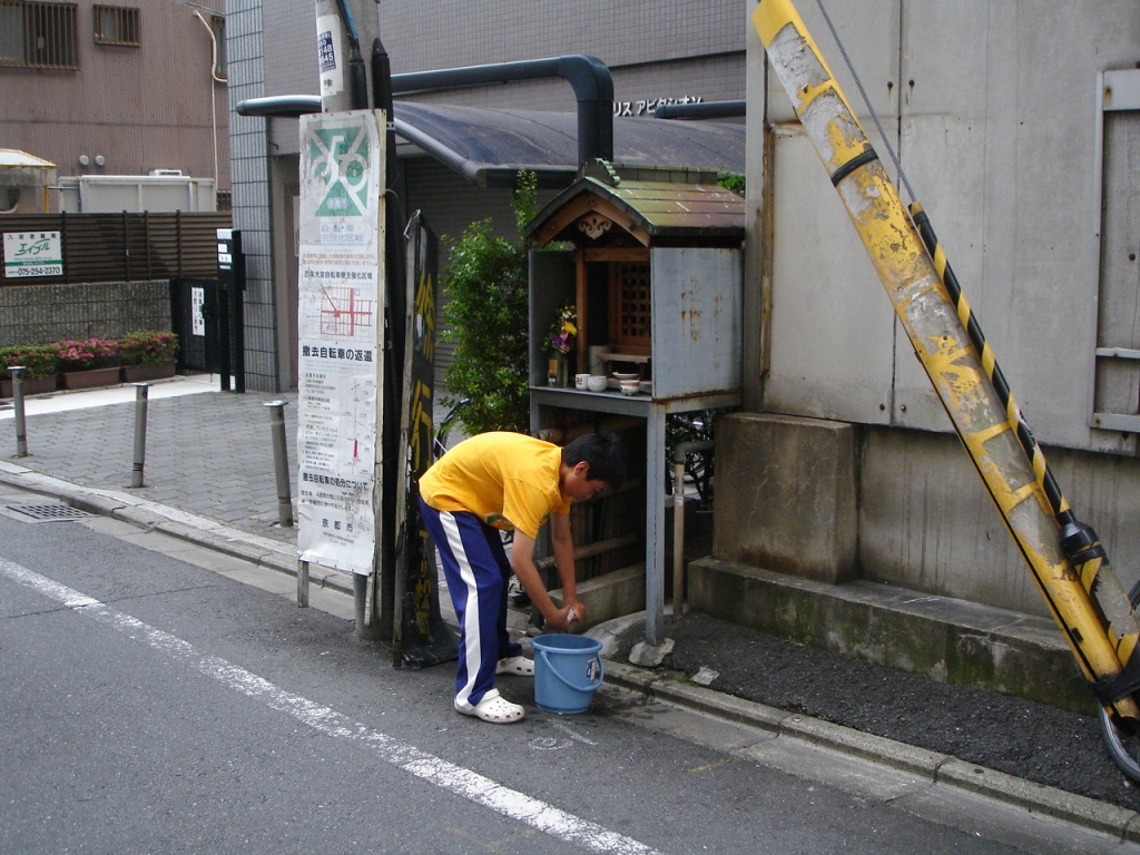 a man with a bucket next to a sign and a building