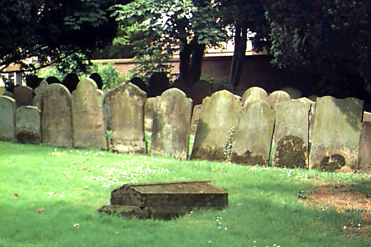 old gravestones at a cemetery with a brick wall