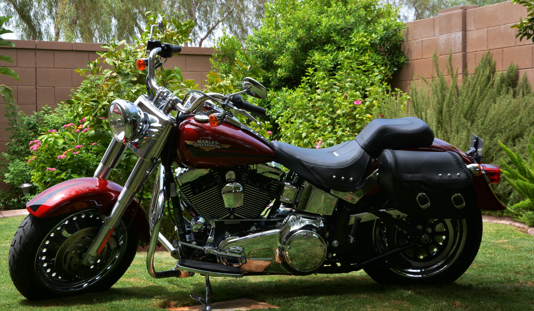 the motorcycle is parked in the yard next to some plants