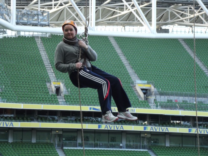 man wearing a scarf on his head hanging from the ropes of a stadium