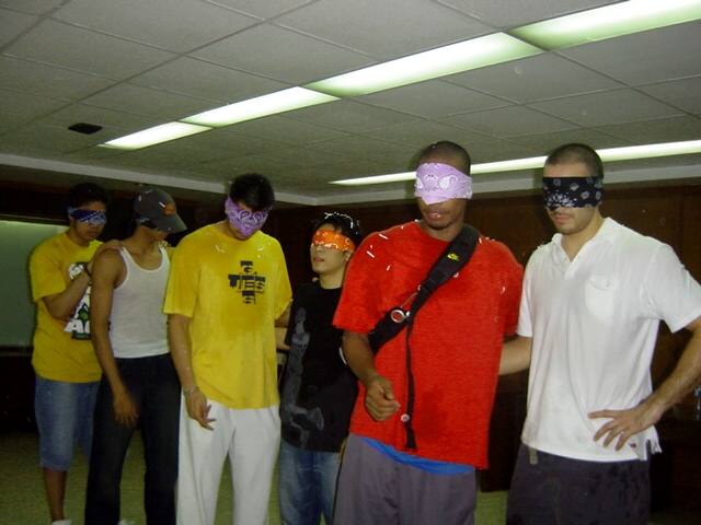 a group of people in blindfolds with one looking at the camera