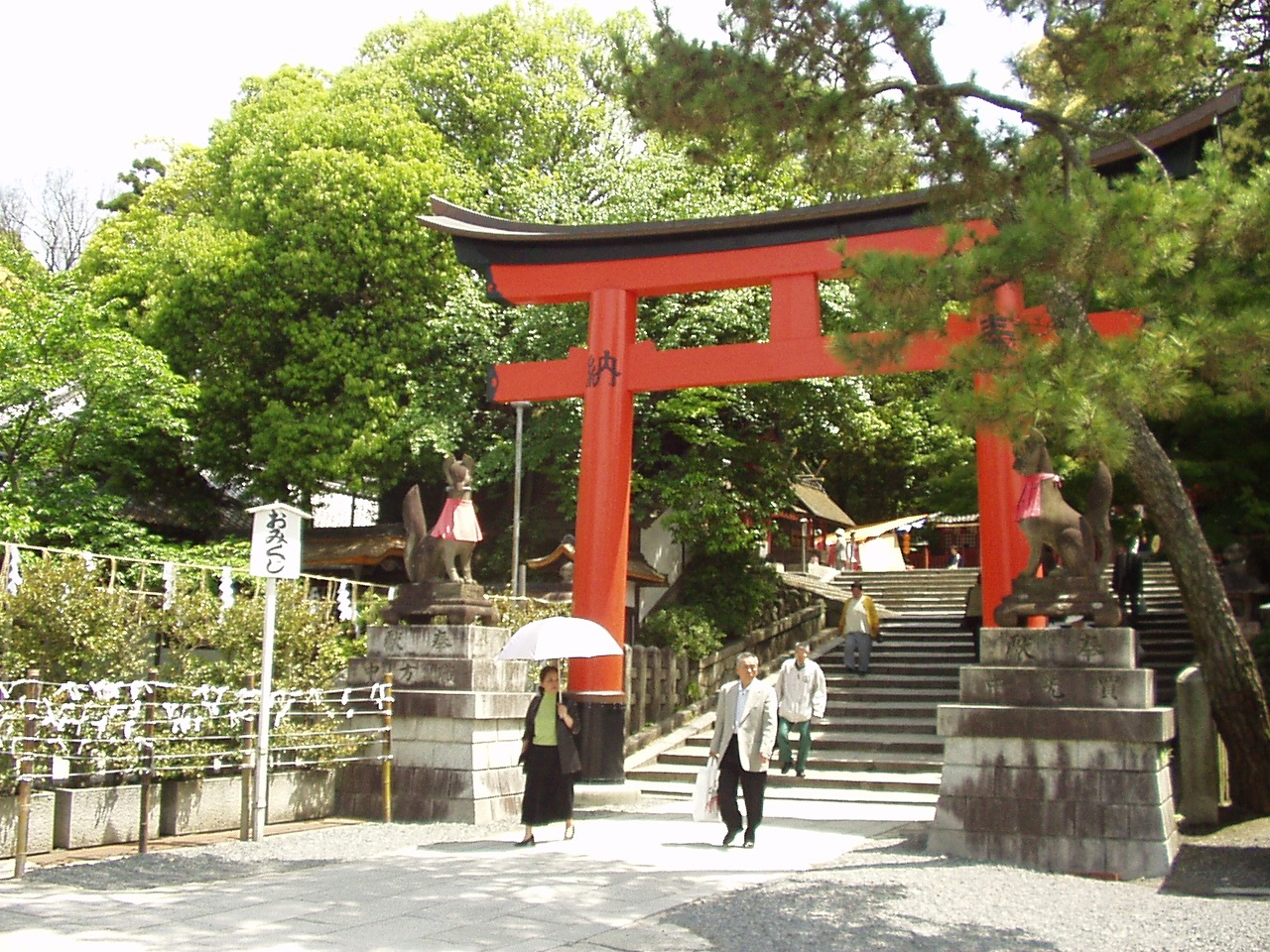 the asian gate features a tori tori tori shrine and people carrying umbrellas