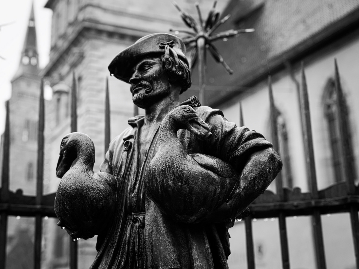 a statue that looks like a fisherman with two birds in his hands