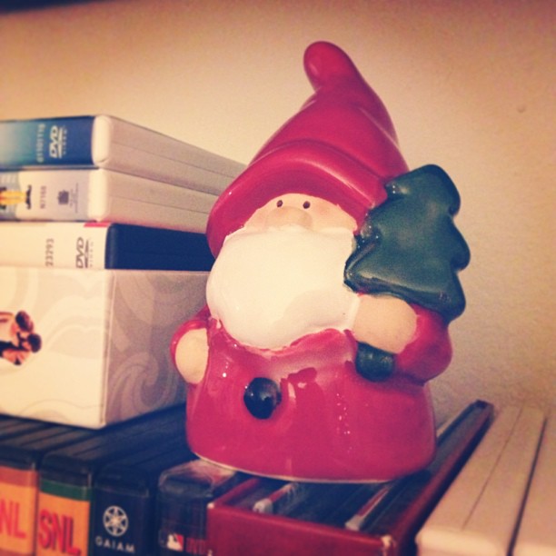 a santa clause christmas ornament in front of two books on a shelf