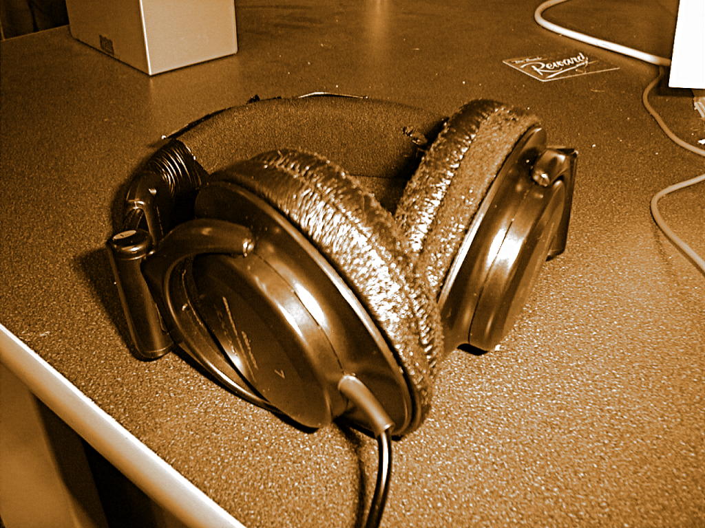 a silver headphone on a table, with cable connected