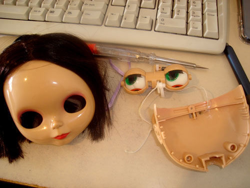 a face mask sitting next to some fake scissors and a toy doll