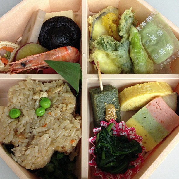 a four compartment bento lunch is loaded with different items