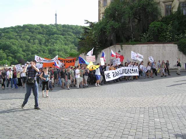 a crowd gathered outside of an office building with people holding signs