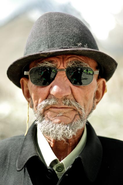 an old man wearing sunglasses and a hat with green light
