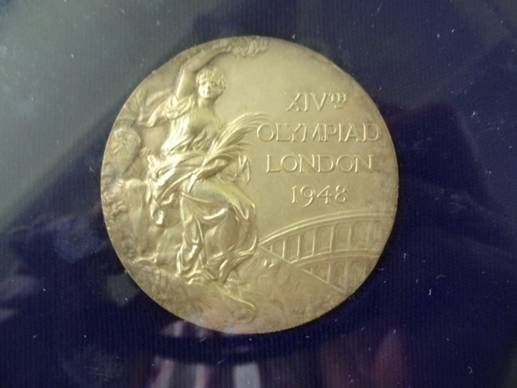 a gold medal of a horse and rider, on display in a case