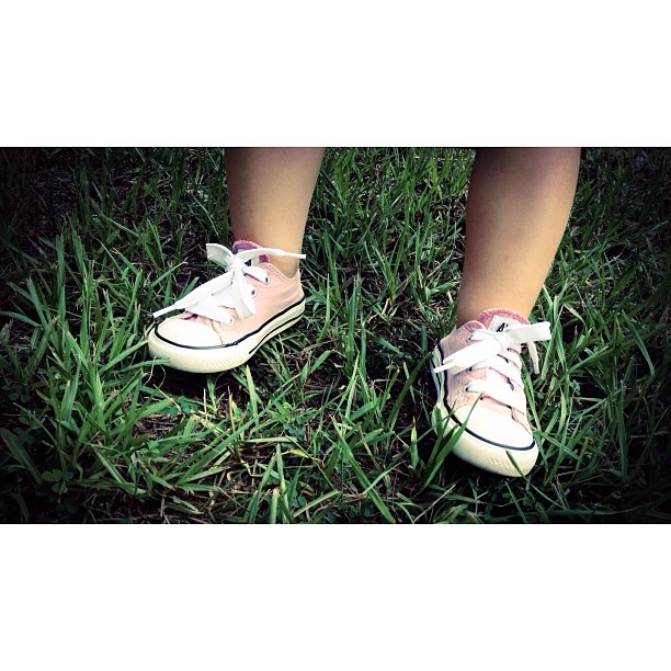a person standing on grass with pink shoes