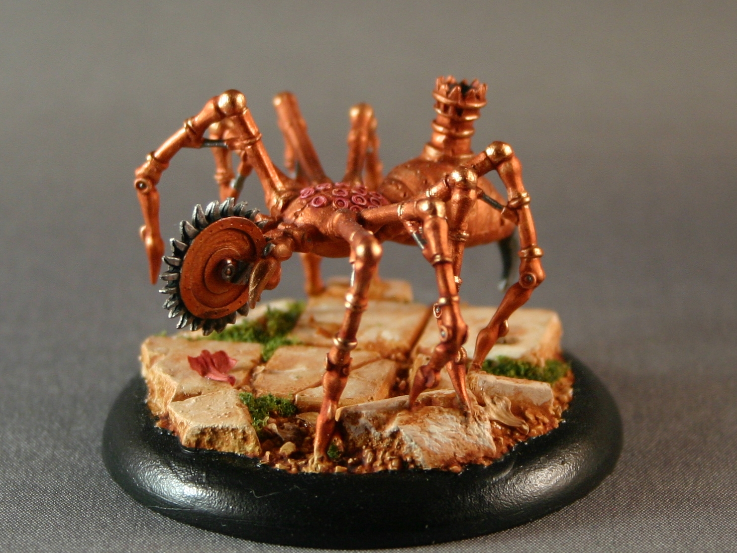 a model of a metal spider with a rusty gear wheel