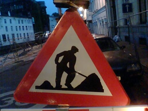 a warning sign that a man is shoveling a dump