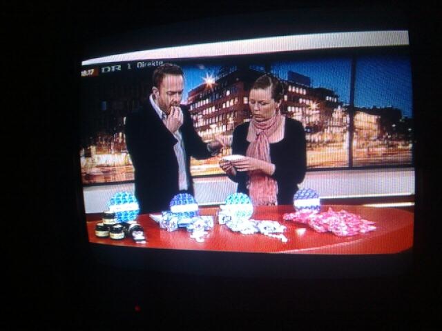 a news anchor and two people play dice on a television