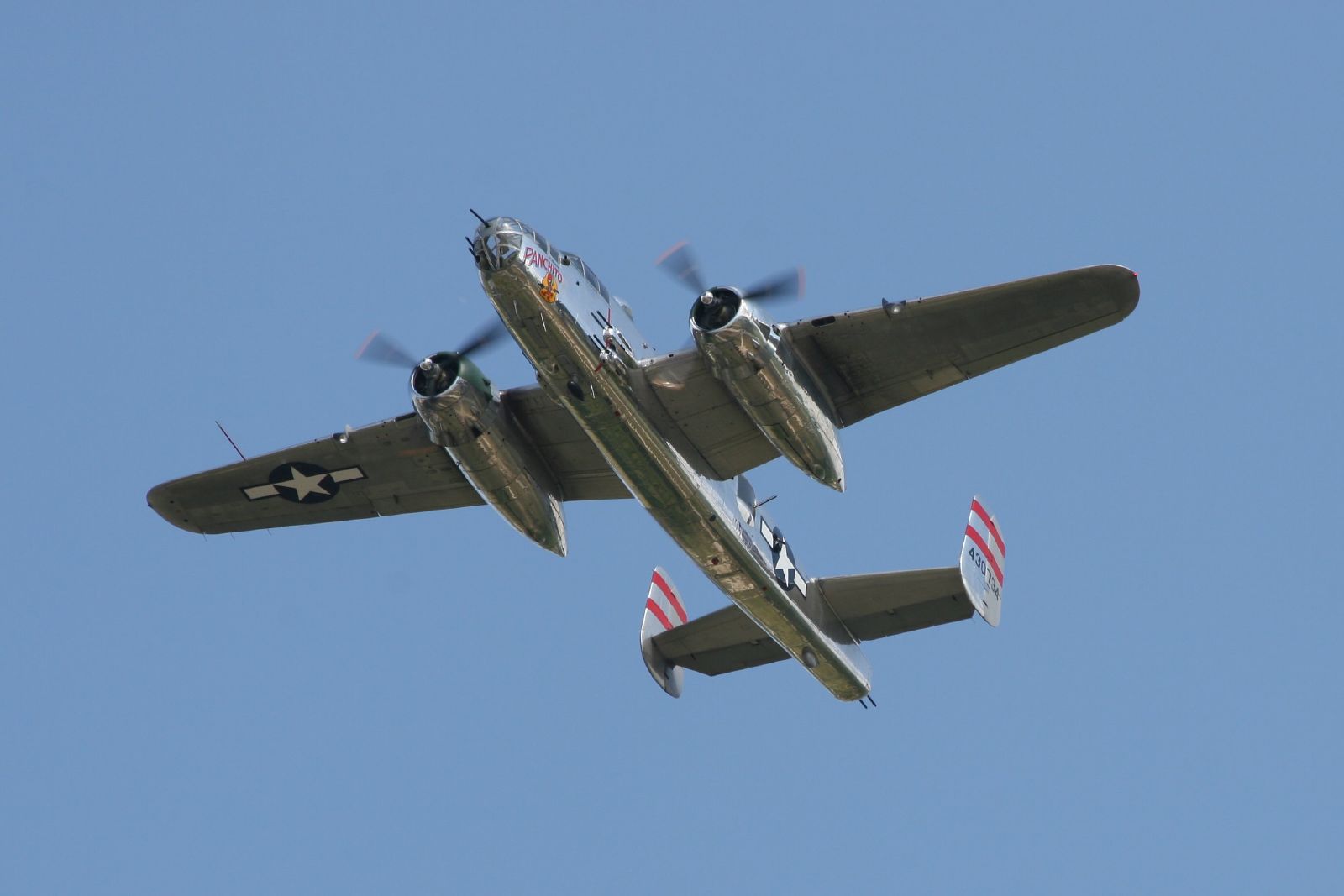 two old world war ii military planes flying in a blue sky