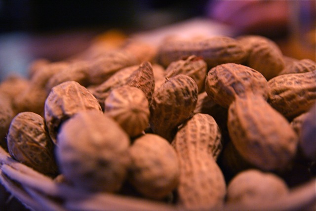 a basket of peanuts sits next to other nuts