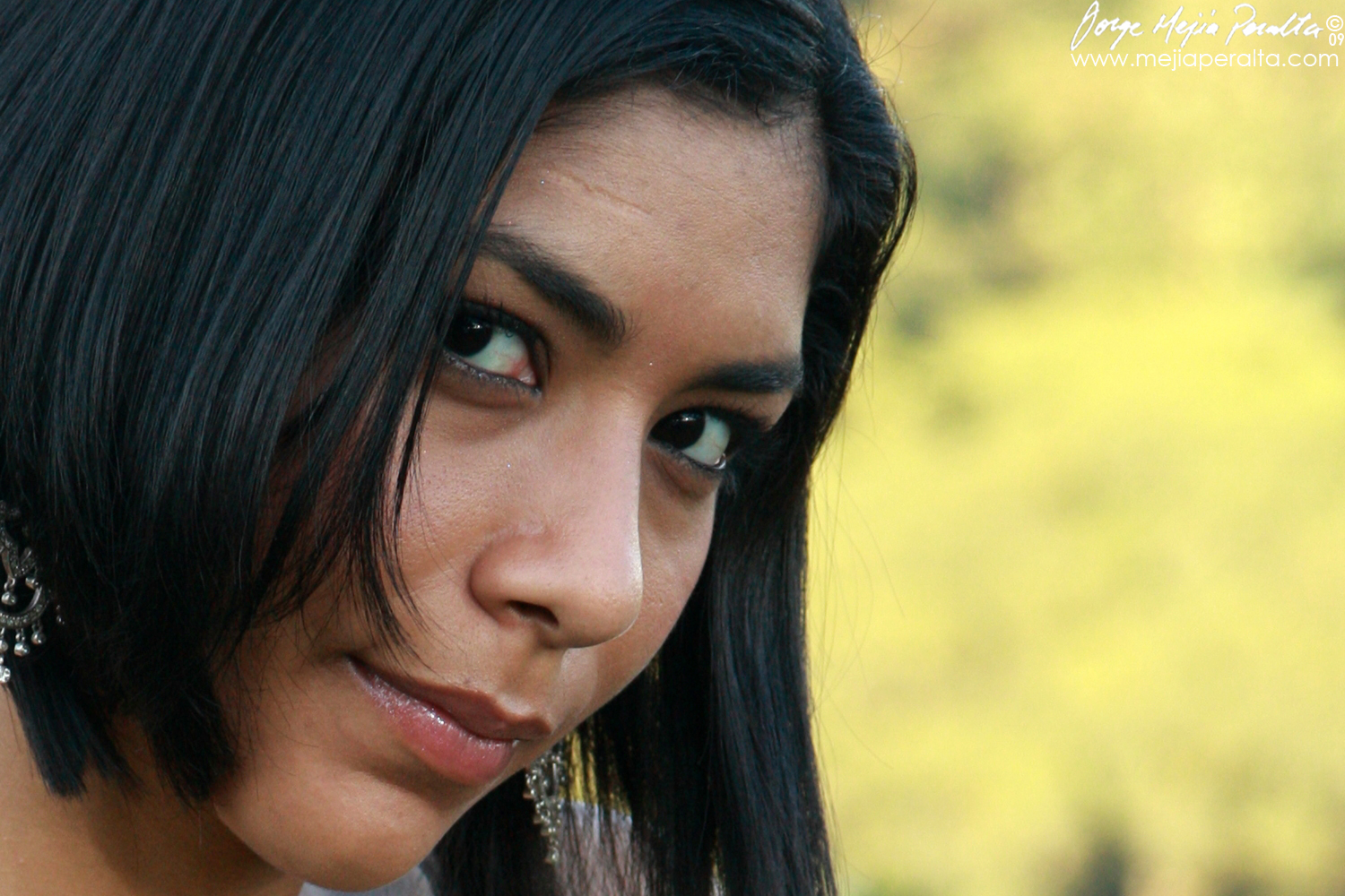 woman with black hair and earring and face looking at the camera