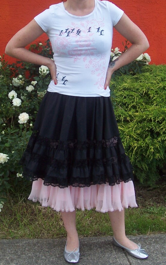 a girl wearing a white t - shirt, black and pink ruffle skirt, silver metallic pumps