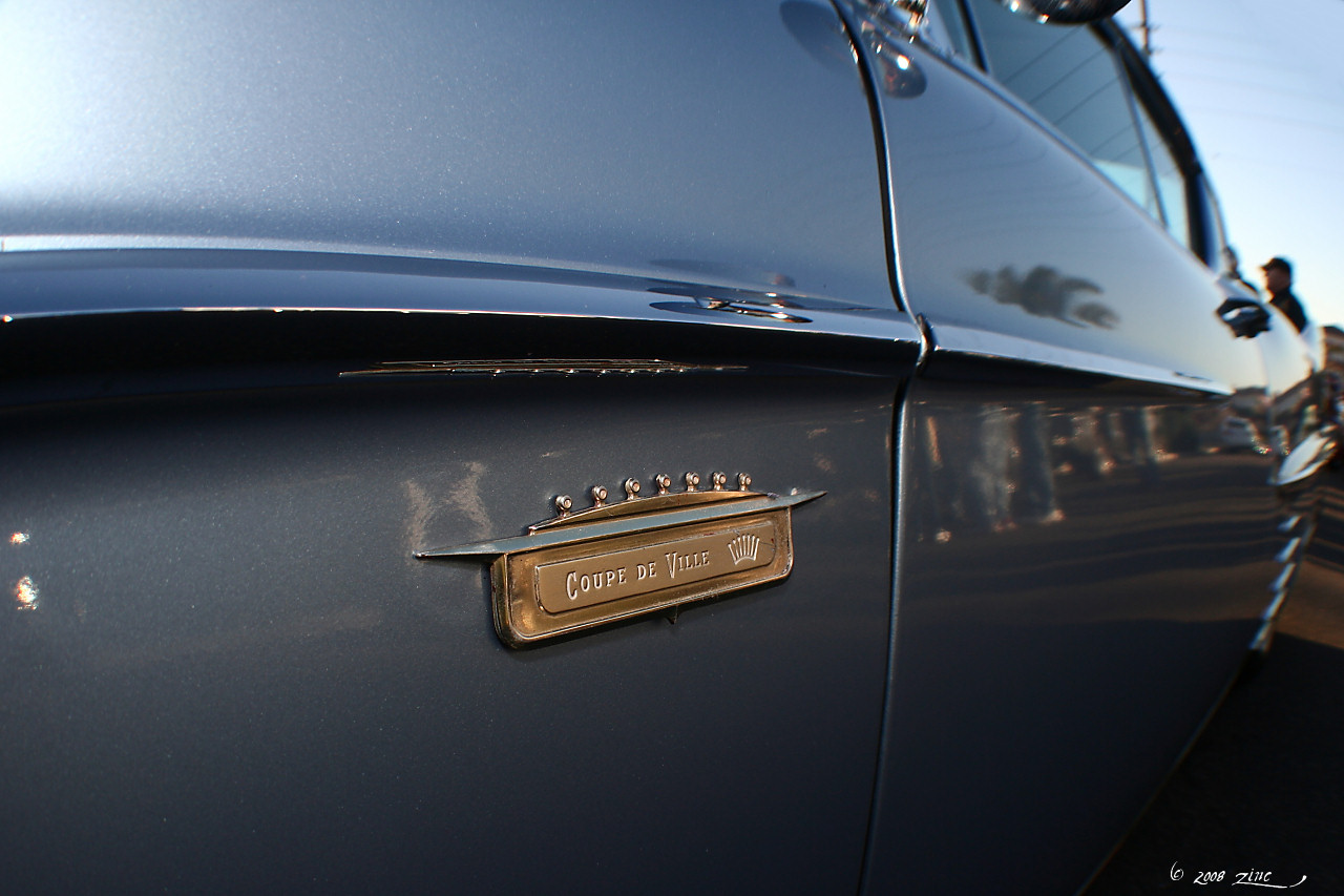 the front part of a classic car with a chrome name plate