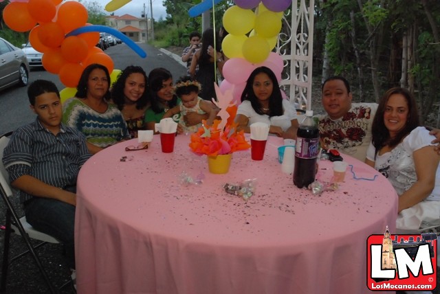 several people gathered around a table with balloons, confetti and cups