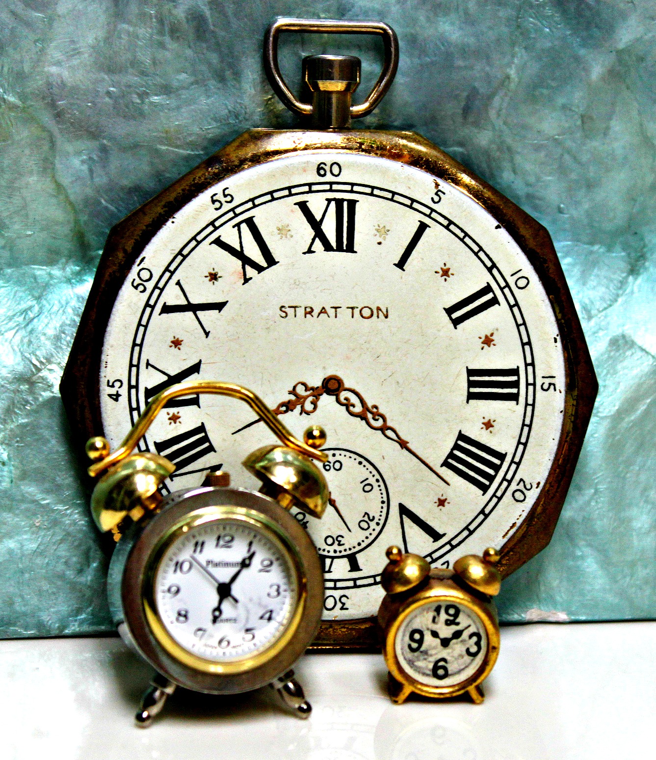 an antique pocket watch and two toy clocks