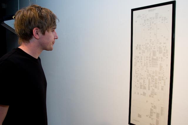 a man standing next to a white wall near a drawing
